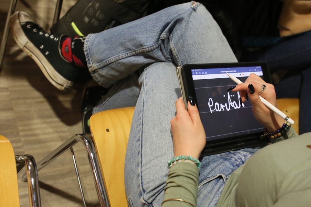 Auf dem Bildschirm eines Tablets steht das Wort "Parität" geschrieben. Eine junge Besucherin macht sich darauf Notizen während des Vortrags der Landesgleichstellungsbeauftragten Manuela Dörnenburg